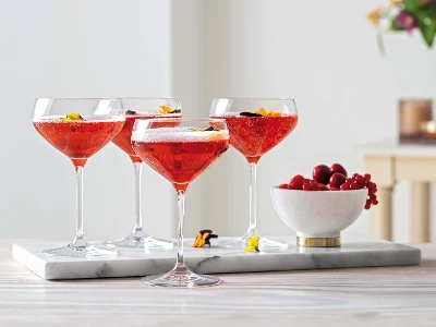 Four champagne glasses from the Purismo collection with berries on a tray.