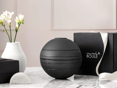 A black La Boule dinnerware set on a table with a black gift box behind it.