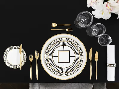 Elegant dining table decoration with gold-patterned MetroChic plates, gold cutlery and crystal glasses viewed from above.