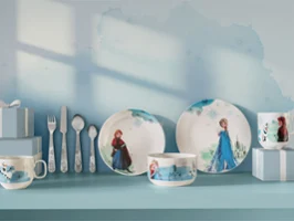 Children's tableware and utensils featuring Frozen characters, displayed with blue gift boxes on a blue shelf.