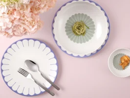 Assiette, bol et coupe de la collection Fleur de Villeroy & Boch avec des plats et des fleurs roses sur un fond rose clair.