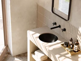 Modernes Badezimmer mit beiger Waschtischplatte und schwarzem Loop & Friends Waschbecken. Zu den Accessoires gehören Handtücher und Toilettenartikel.