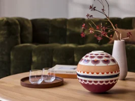 Eine La Boule Kyoto und ein Tablett mit Gläsern auf einem hölzernen Couchtisch vor einem grünen Sofa.