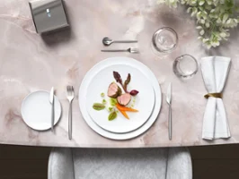 Stilvoller Marmortisch mit Gourmet-Gericht auf weißen MetroChic Tellern, begleitet von MetroChic Besteck und Blumendekoration.