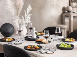 A dining table with a black La Boule being used for food as well as a fully assembled La Boule for decoration.