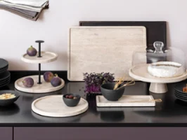 Manufacture Travertine et Manufacture mise en scène habile Plan de travail de cuisine avec des plateaux élégants en travertin de fabrication, sur lesquels sont présentés des figues, du brie, du pain et un bol de légumes.