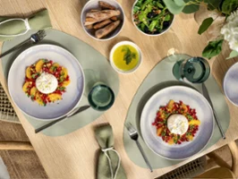 Two Perlemor plates in beige with salad and burrata cheese Two plates of salad with burrata cheese, served with bread, green salad and a bowl of olive oil on a dining table.