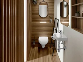 Modernes Badezimmer mit Holzvertäfelung, wandhängendem WC mit ovalem Spiegel, kleinem weißen Waschbecken mit großem Spiegel und Regal mit Utensilien. Rechts steht eine Leiter mit schwarzem Rahmen als Dekoration und Ablage.