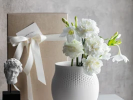 Manufacture Collier Blanc Big Perle Vase A generous-sized Manufacture Collier Blanc Perle vase with a delicate dotted texture, wrapped gift behind, designed for lush floral arrangements.