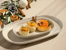 Three assorted pastries on a Perlemor white oval plate Three assorted pastries on a Perlemor white oval plate, with dried orange slices and cinnamon sticks in the background.