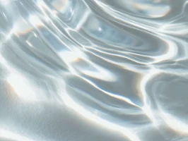 Das Sonnenlicht wird von den sanften Wellen des klaren Wassers reflektiert und erzeugt helle, wellenförmige Muster auf der Oberfläche.