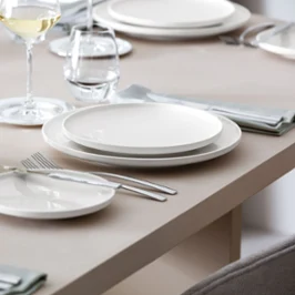 Table dressée avec de la vaisselle Afina qui donne l’impression de flotter dans l’air Une table dressée avec des assiettes Afina vues de côté pour voir l’effet aérien des assiettes qui semblent flotter dans l’air.