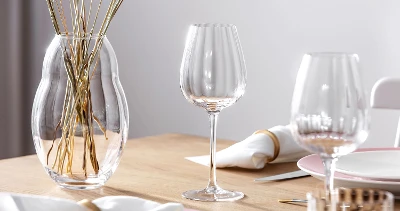 Elegant table decoration with a clear Rose Garden wine glass, a vase with dried stems and fine dinnerware.