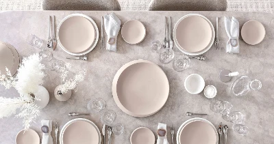 Et bord dekket med Villeroy & Boch NewMoon-tallerkener i beige og hvitt samt bestikk og glass.