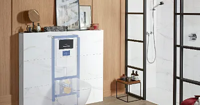 A modern bathroom with a shower with glass cabinet, a toilet system concealed behind a marble countertop, wooden wall panels and a small black table with toiletries and decoration objects.