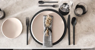 Une décoration de table moderne avec de la vaisselle NewMoon en beige et des couverts de table Manufacture noirs.