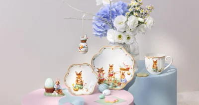 Assorted Annual Easter edition 2026 dishware with bunny designs displayed with flowers and decorative eggs on pastel stands.