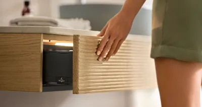 Dans une salle de bains, une femme ouvre un tiroir de console de la collection de meubles de salle de bains Antao de Villeroy & Boch.