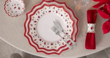 A festively laid table A festively laid table with red-and-white patterned crockery, a red napkin, and a knife and fork on a round table.