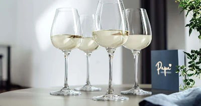 Trois verres de vin blanc de la collection Purismo sur une table avec une carte de vœux en arrière-plan.