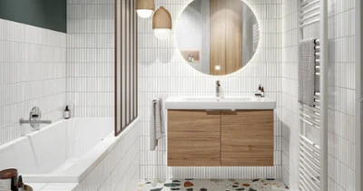 Une salle de bains avec un lavabo Architectura blanc, un meuble en bois avec un miroir rond et éclairé, des lampes suspendues et un radiateur blanc sur la droite. Sur le côté gauche se trouve une baignoire blanche avec une robinetterie grise.