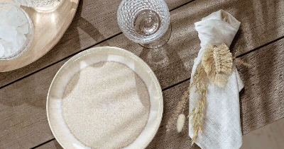 A beige Perlemor plate and a napkin on a wooden table.