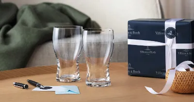 Two Purismo beer glasses from Villeroy & Boch as a gift with card and fountain pen and gift box in the background