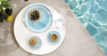 Das Perlemor Aqua Geschirr ist in einem sommerlichen Arrangement neben einem Pool mit kleinen Köstlichkeiten  angerichtet.