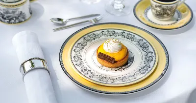 A small dessert with yellow topping and whipped cream on a decorative plate from the Audun collection by Villeroy & Boch. 