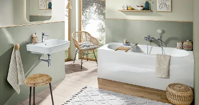 Une salle de bains avec des murs verts, des meubles en bois et une baignoire blanche ainsi qu’un lavabo blancs O.novo.