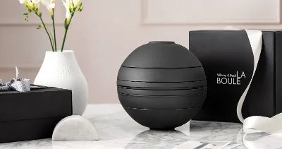 Een zwart La Boule serviesset op een tafel met erachter een zwarte cadeaubox.