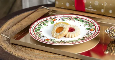 Christmas biscuits on a festive Winter Bakery Delight plate with a gift in the background.