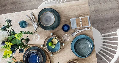 Une table en bois avec des assiettes Lave de Villeroy & Boch posées dessus.