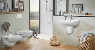 Modern bathroom with a toilet, bidet, washbasin and shower from the O.novo collection The modern bathroom with beige-coloured tiles and pastel-coloured walls is fitted with an O.novo wall-mounted toilet, a bidet, a washbasin with a mirror and a walk-in shower. On the shelves there are framed artworks and toiletries. There are baskets on the floor.