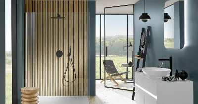 Une robinetterie de douche Universal Showers noire dans une salle de bains en bleu pétrole avec de grandes fenêtres et un lavabo.