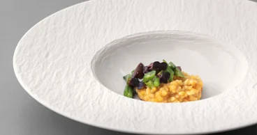 Manufacture pasta plate with food on it on a grey table.