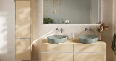 Moderne Boho-bad fra Villeroy & Boch med veggmontert Venticello-toalett og bidé på rullesteinsgulv. En dekorativ plante og en kurv står på en trehylle over.