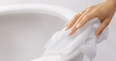 Cleaning toilet ceramics A hand wearing a ring wipes a white cloth over a white ceramic toilet.