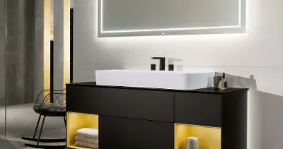 Un lavabo Finion avec meuble sous plan éclairé et miroir lumineux dans une salle de bains sombre.