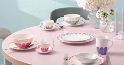 A round table setting with plates, mugs, cups, cutlery, glasses, and white flower vases from Villeroy & Boch Fleur.