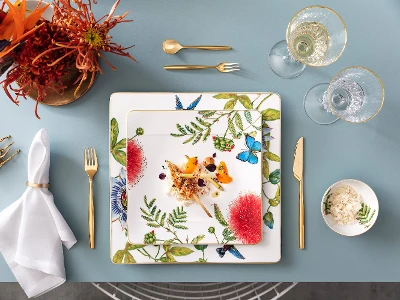 Ein gedeckter Tisch mit Amazonia-Tellern, mit goldenem MetroChic Besteck von Villeroy & Boch.