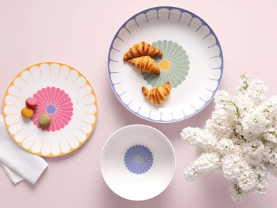 Three Villeroy & Boch Fleur plates Three Villeroy & Boch Fleur plates with croissants and macarons next to white flowers on a light pink background.