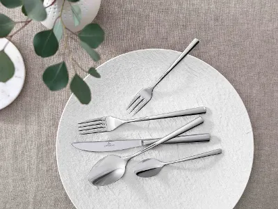 Une décoration de table élégante avec des couverts de table Piemont modernes et de verdure décorative sur une nappe neutre.