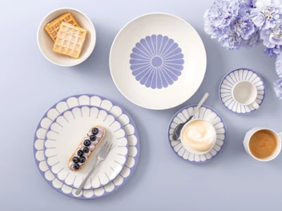 Table setting with Villeroy & Boch Fleur Bleu plates Table setting with Villeroy & Boch Fleur Bleu plates, coffee, dessert, waffles, and light purple flowers on a light background.
