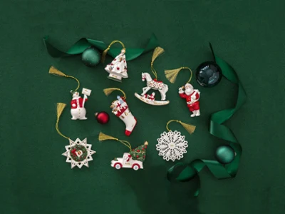 Des décorations de Noël Annual Christmas Edition 2024 sur fond vert Des décorations de Noël Annual Christmas Edition 2024 avec un Père Noël, un flocon de neige et un cheval à bascule sur fond vert avec un ruban vert et des décorations en forme de boules.