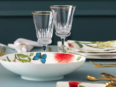 Élégant service de table composé de verres en cristal, d'un bol avec des motifs de papillons et de fleurs et d'assiettes avec des motifs floraux sur fond bleu-vert. Élégant service de table composé de verres en cristal, d'un bol avec des motifs de papillons et de fleurs et d'assiettes avec des motifs floraux sur fond bleu-vert.
