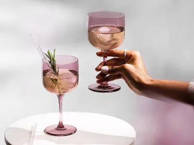 Woman arm holding like grape wine glass, showcasing the beautiful colors of the collection.