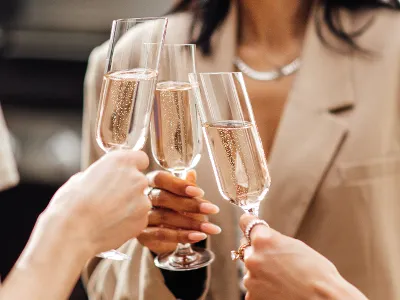 Three people dressed in neutral colours making a toast with Villeroy & Boch NewMoon champagne glasses.