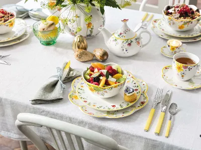 Ein farbenfroher Osterbrunch-Tisch, gedeckt mit floralem Spring Awakening Geschirr und einer Schüssel voller Früchte. 