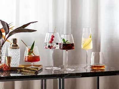 Various cocktails in elegant MetroChic glasses on a marble table next to a plant.